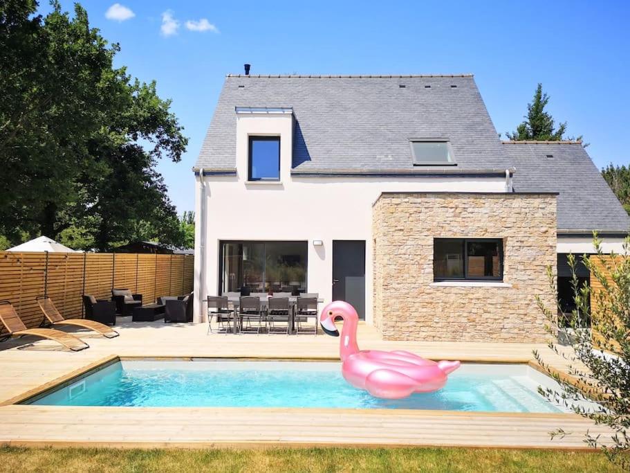 un flamingo rose dans une piscine en face d'une maison dans l'établissement Piscine - Maison Moderne - Route des Plages, à Saint-Philibert