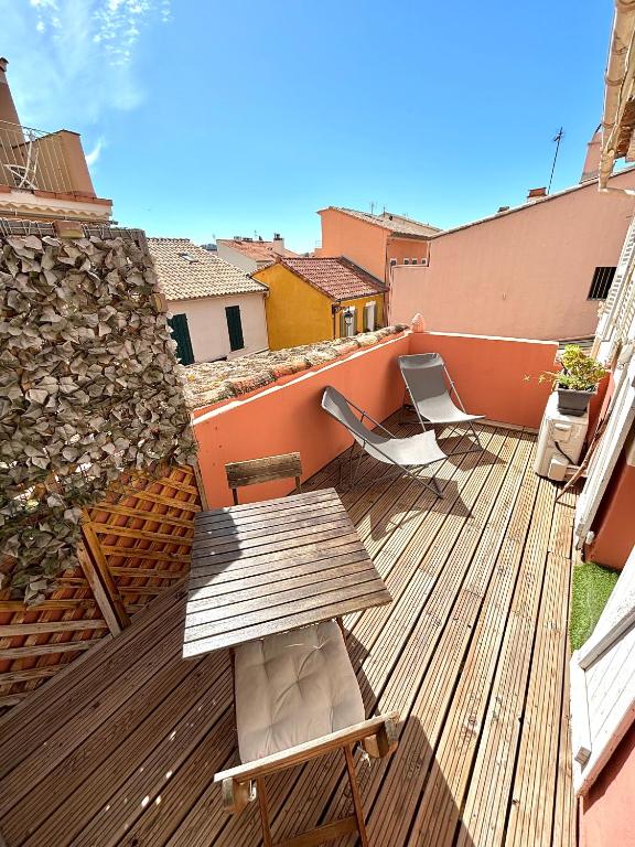 une terrasse en bois avec une table et des chaises dessus dans l'établissement Studio terrasse Sanary centre ville rue piétonne, à Sanary-sur-Mer