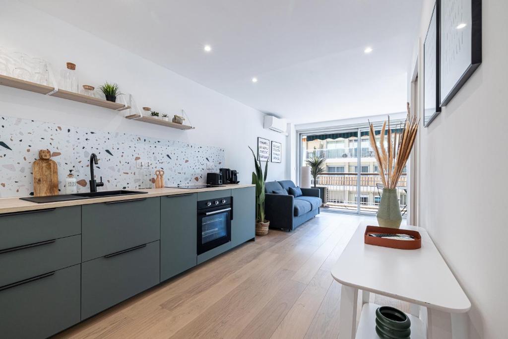 Il comprend une cuisine et un salon doté d'un canapé bleu. dans l'établissement 2 pièces cosy en centre ville, à Cannes