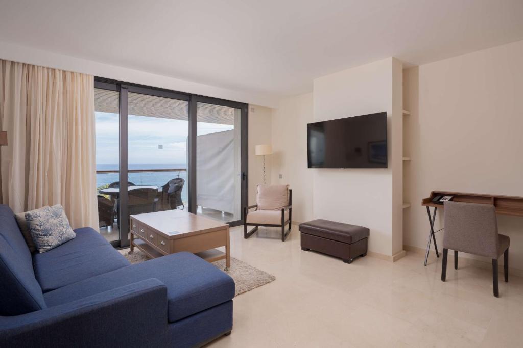 a living room with a blue couch and a table at Radisson Blu Resort Gran Canaria in La Playa de Arguineguín