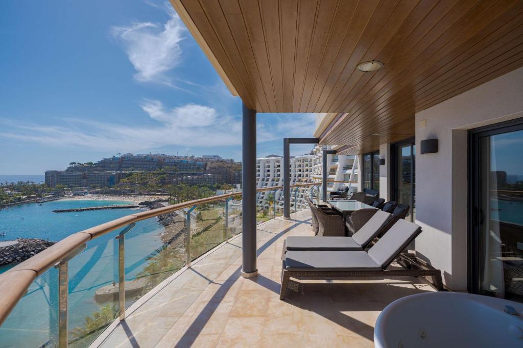 a balcony with chairs and a view of the water at Radisson Blu Resort Gran Canaria in La Playa de Arguineguín