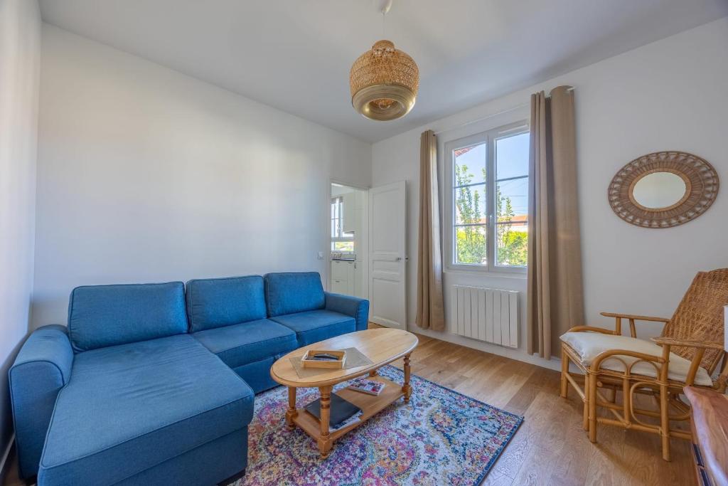 un salon avec un canapé bleu et une table dans l'établissement La Maison du Fleuve - Welkeys, à Dives-sur-Mer