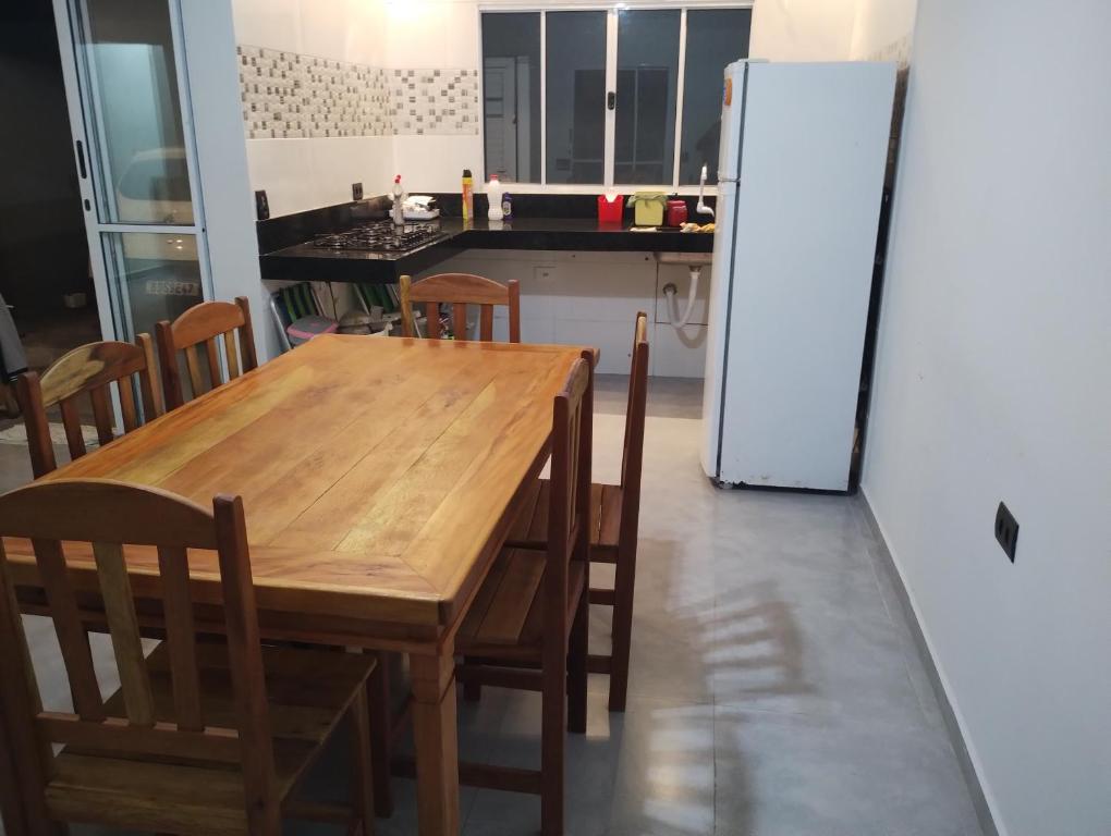a kitchen with a wooden table and a refrigerator at Casa de Praia Golfinhos in Caraguatatuba