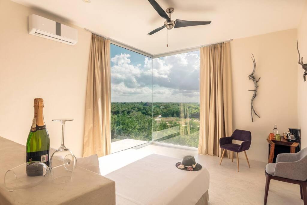 ein Wohnzimmer mit großem Fenster und einer Flasche Wein in der Unterkunft Crystal Nest SunSet View in Holbox