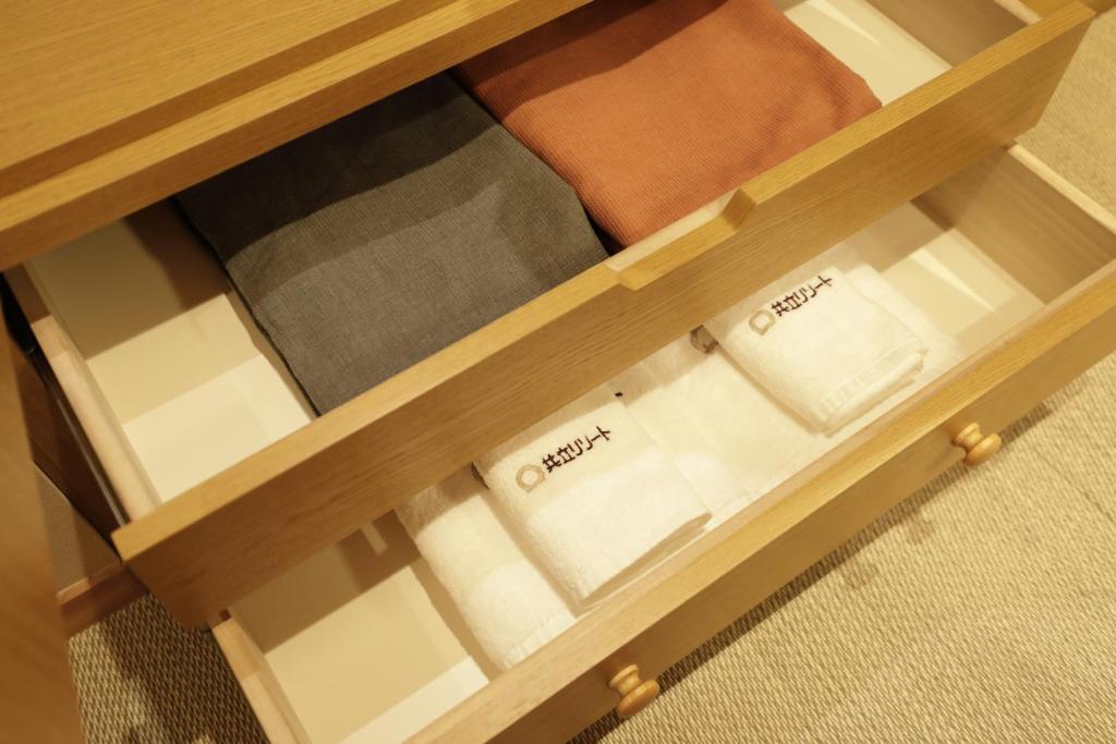 un tiroir en bois avec des serviettes blanches dans une table en bois dans l'établissement Onyado Yuinosho, Shirakawago, à Shirakawa-gō