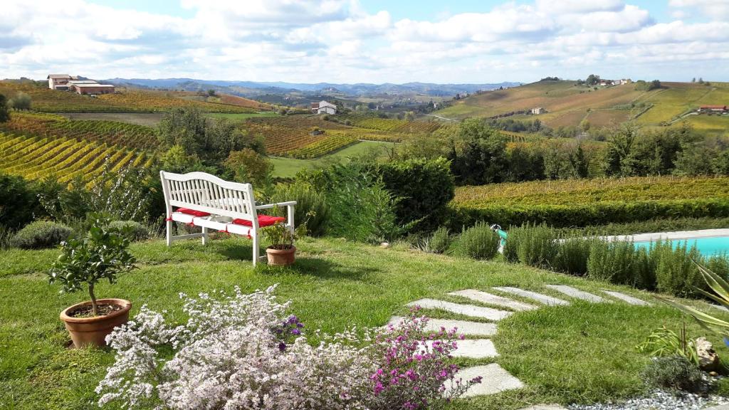 a white bench sitting in the grass next to a pool at Casa LuceSole in Fontanile