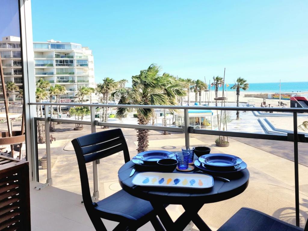 une table avec de la vaisselle bleue sur un balcon avec la plage dans l'établissement Canet-en-Roussillon T2, 4 pers, Clim, face mer - FR-1-794-106, à Canet