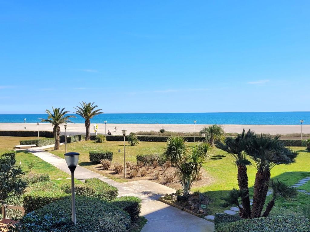 un parc avec des palmiers et la plage dans l'établissement Canet-en-Roussillon - T2 moderne 4 pers, accès direct plage, terrasse vue mer - FR-1-794-103, à Canet
