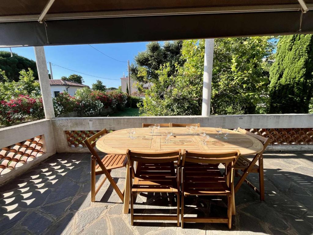 une table et des chaises en bois sur une terrasse dans l'établissement Maison 3 pièces avec jardin, à 2 pas du centre, 8 couchages, parking, clim et ménage inclus - FR-1-226B-208, à Cavalaire-sur-Mer