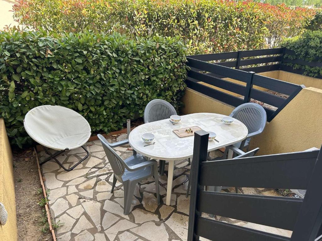 une table blanche et des chaises assises sur une terrasse dans l'établissement Studio cabine confortable, terrasse, proche plage et commerces - Le Grau du Roi - FR-1-250-284, au Grau-du-Roi