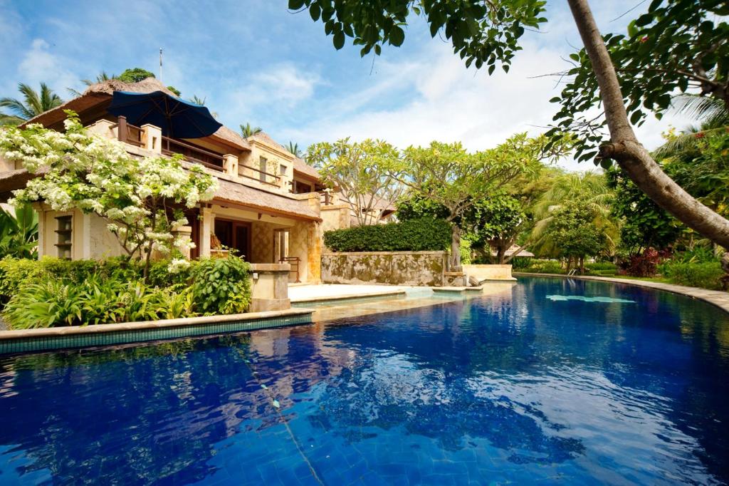 a swimming pool in front of a house at Pool Villa Merumatta Senggigi in Senggigi