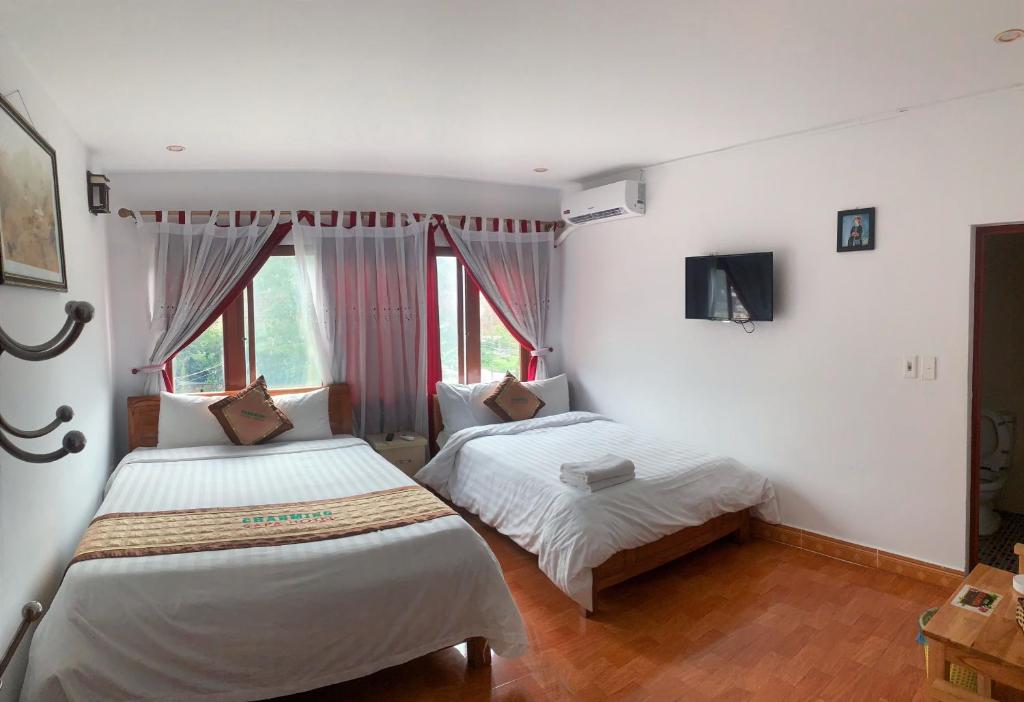 une chambre avec deux lits et une télévision au mur dans l'établissement olivia Hotel, à Sa Pa