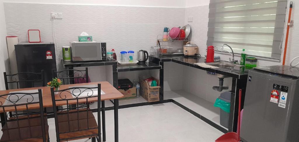 a kitchen with a counter and a table and a sink at Alya Homestay 295 Sik in Sik