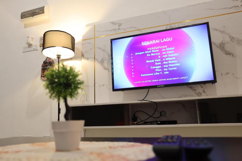 a flat screen tv on a wall with a potted plant at Homestay Az Zikri D' Sepat in Kuantan