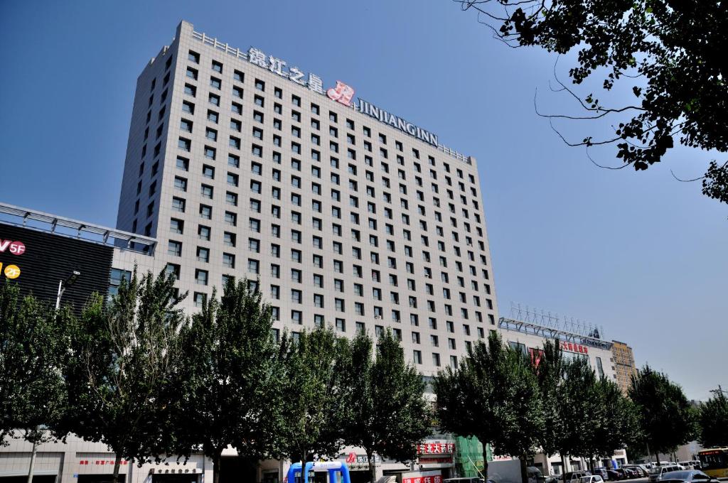 瀋陽的住宿－錦江之星瀋陽張士中央大街店，一座高大的白色建筑,前面有树木