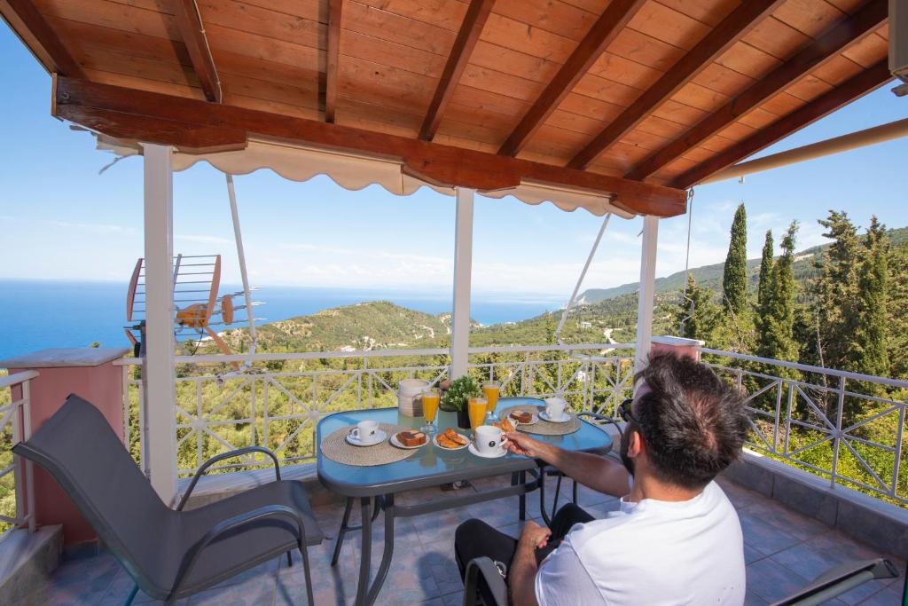 a man sitting at a table on the balcony of a house at Agnantio in Agios Nikitas