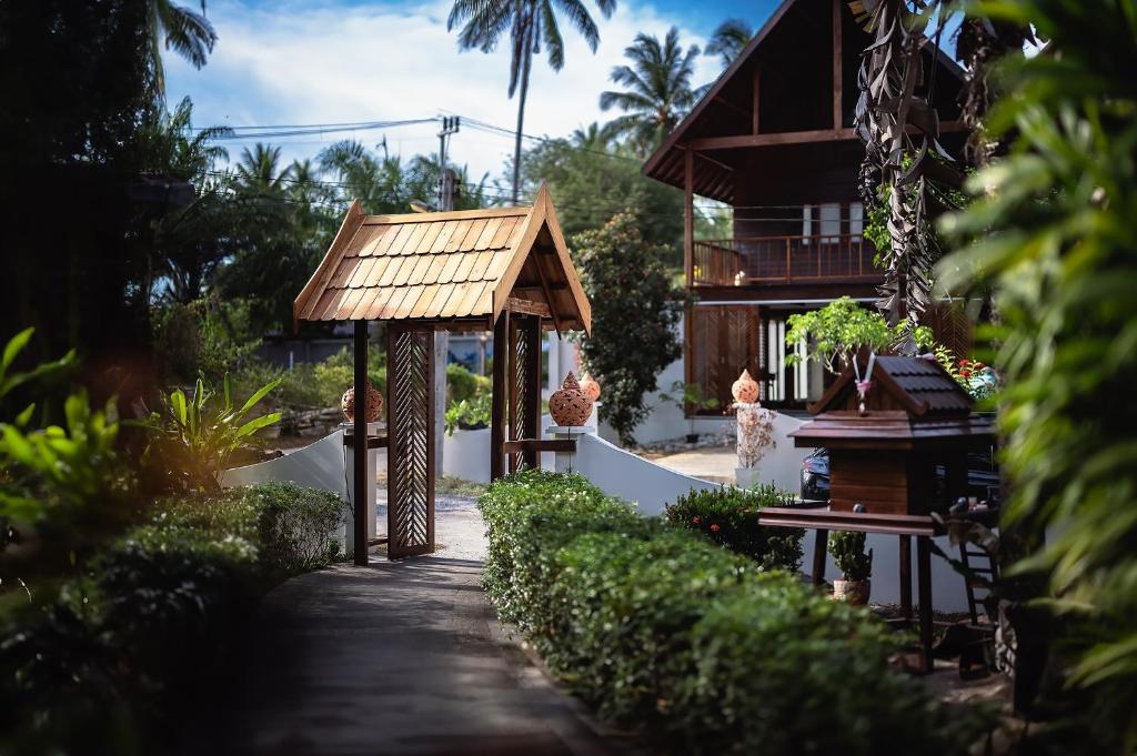 ein Haus mit einem Holzdach und einem Gehweg in der Unterkunft Leeloo Paradise in Khanom