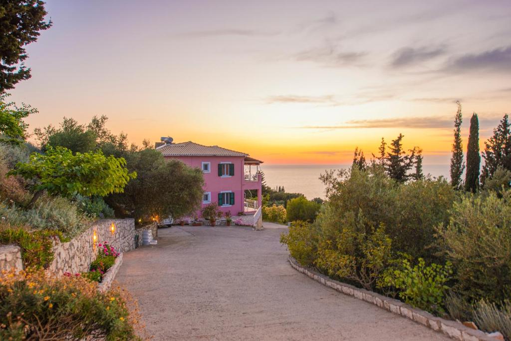 a pink house with the sunset in the background at Agnantio in Agios Nikitas