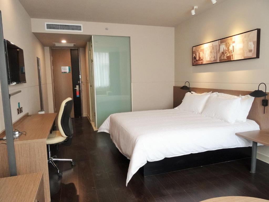 Cette chambre comprend un grand lit et un bureau. dans l'établissement Jinjiang Inn Anyang Antang New City, à Tangyin