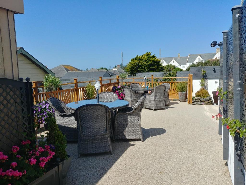 a patio with a table and chairs and flowers at Meadow View Apartments are 2 and 3 bedroomed with private parking in Newquay