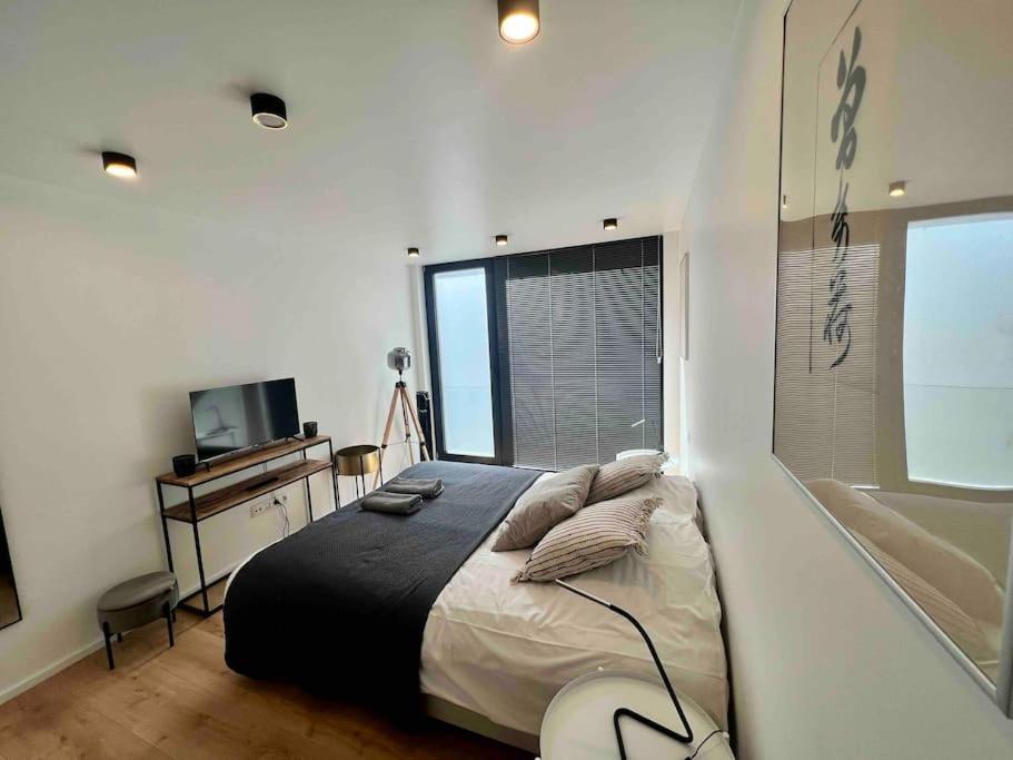 Un dormitorio con una cama grande y un televisor. en Triplex d'architecte en hypercentre, en Lieja