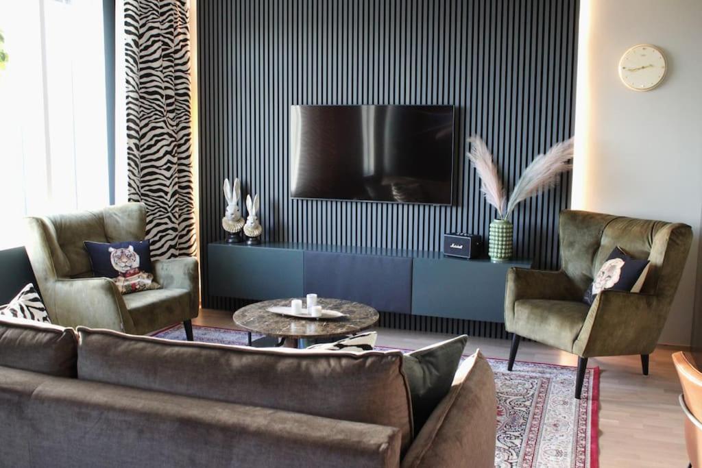 a living room with a couch and two chairs and a tv at Magnificent luxury for you in Tampere
