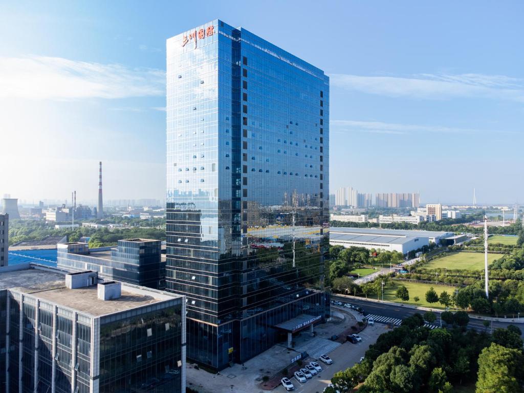 a tall glass building in a city at Echarm Hotel - Wuhan Jingkai Yongwang Sports Center in Wuhan