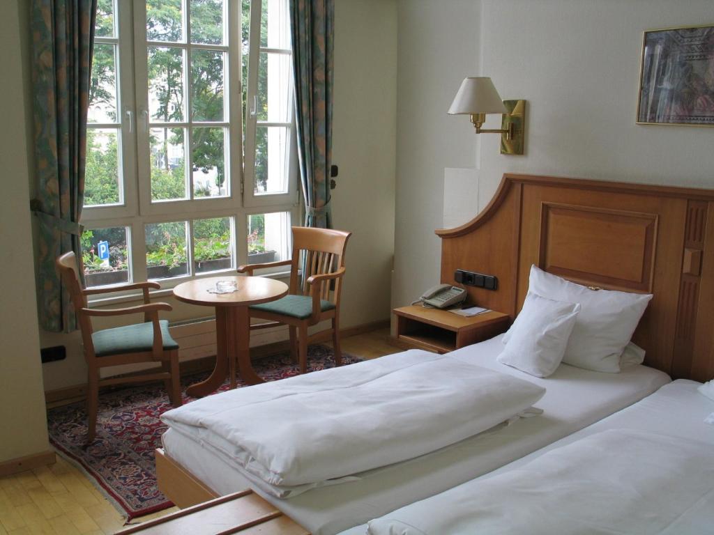 ein Hotelzimmer mit 2 Betten, einem Tisch und einem Fenster in der Unterkunft Hotel Römischer Kaiser in Trier