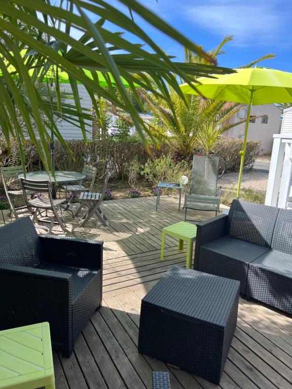 une terrasse avec des chaises, des tables et un parasol dans l'établissement Mobil-home de charme avec deux terrasses, à Vias