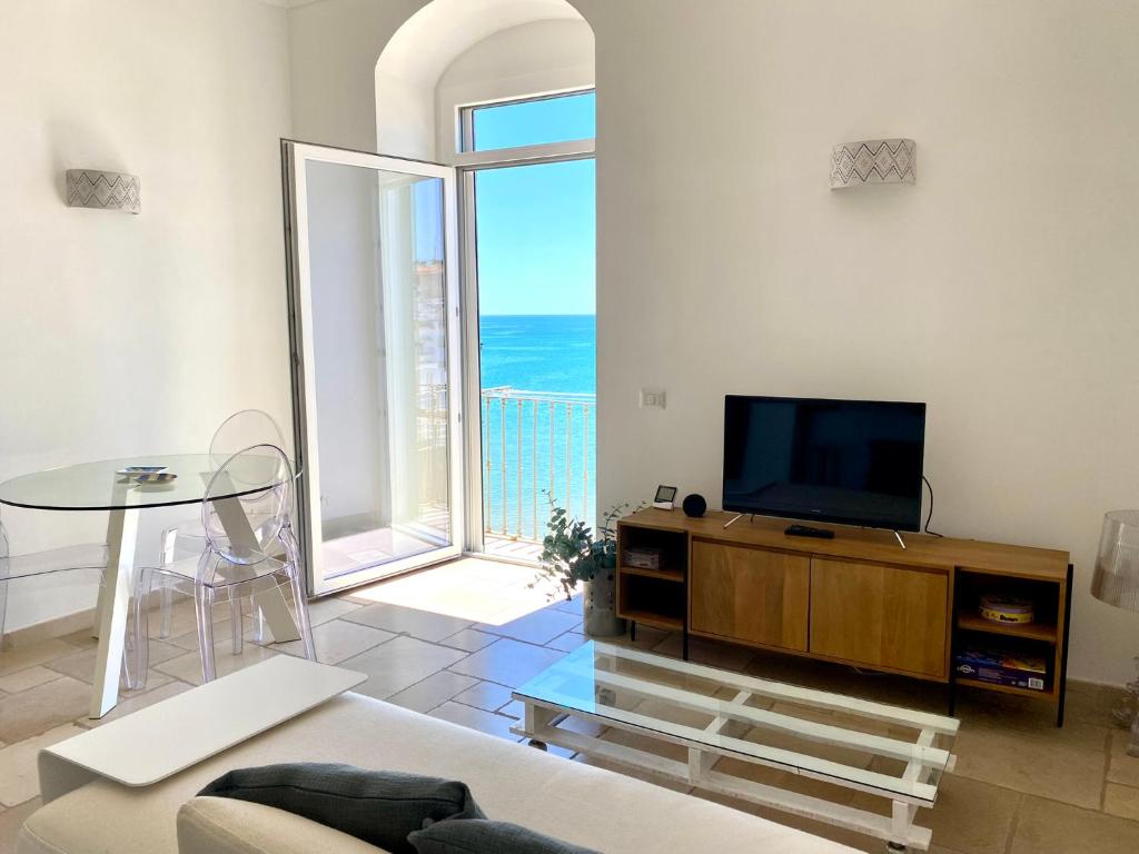 Una sala de estar con un televisor de pantalla plana y una mesa. en Panta Calà, en Vieste