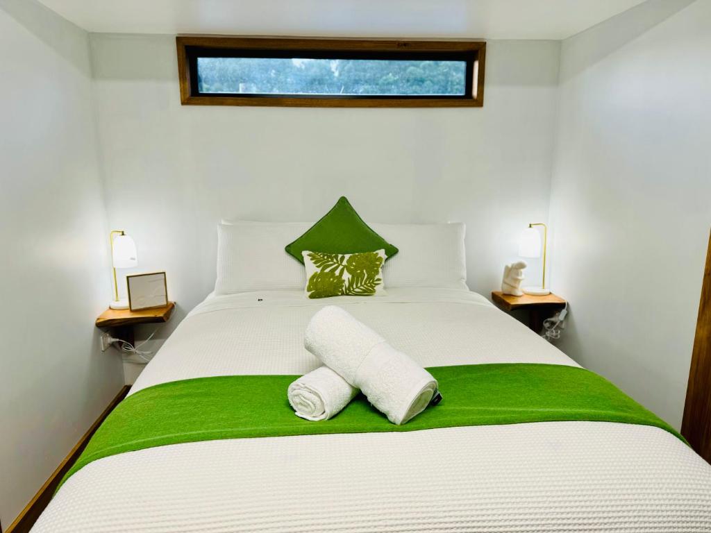 a bedroom with a white bed with two towels on it at GORGE Chocolates Tiny House in Kennedys Creek