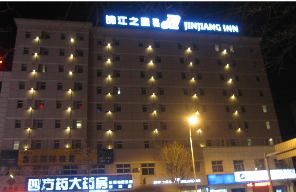 duży budynek z znakiem na górze w obiekcie Jinjiang Inn Shenyang Army General Hospital w mieście Shenyang