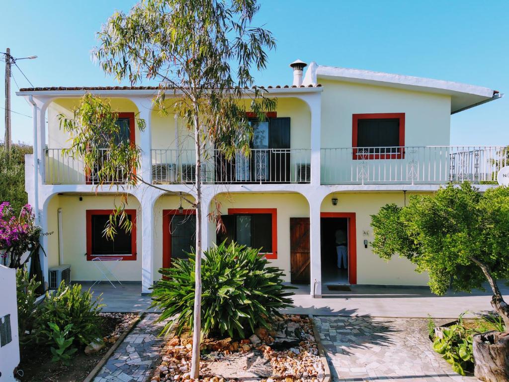 a large white house with red doors and trees at Quinta da Norinha in Portimão