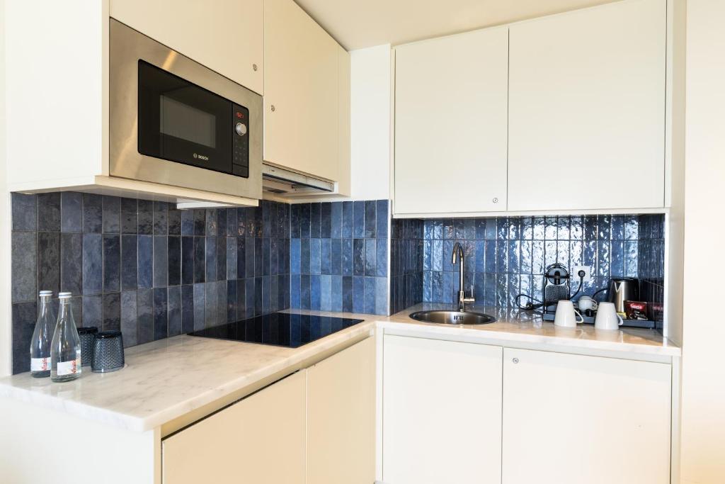 a white kitchen with a sink and a microwave at Crowne Plaza - Caparica Lisbon in Costa da Caparica