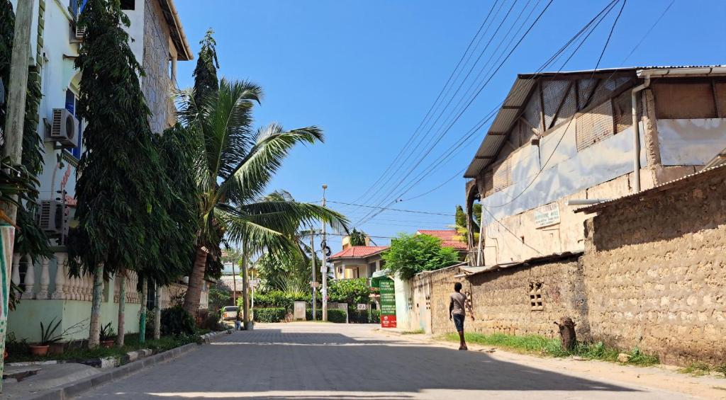 a man walking down a street next to a building at Spacious Two Bedroom Apartment In Mtwapa - Modern Amenities And Prime Location in Mombasa