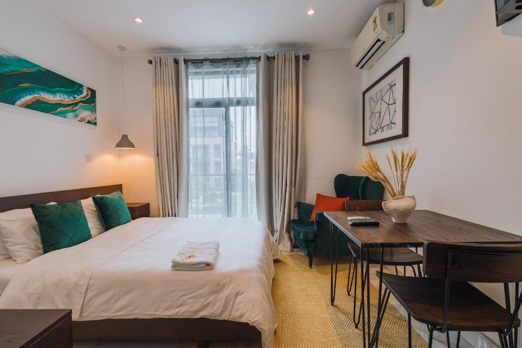 The Avery Studio at Embassy Gardens, Cantonments في آكرا: غرفة نوم بها سرير ومكتب وطاولة