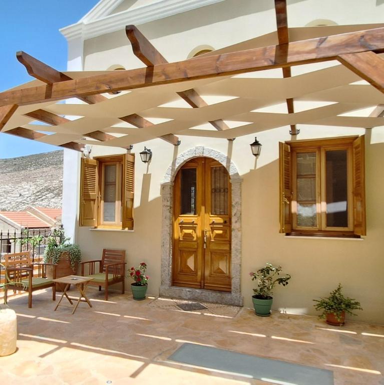 a patio with a wooden pergola in front of a house at To Pefko - Mezzanines - in Meyisti