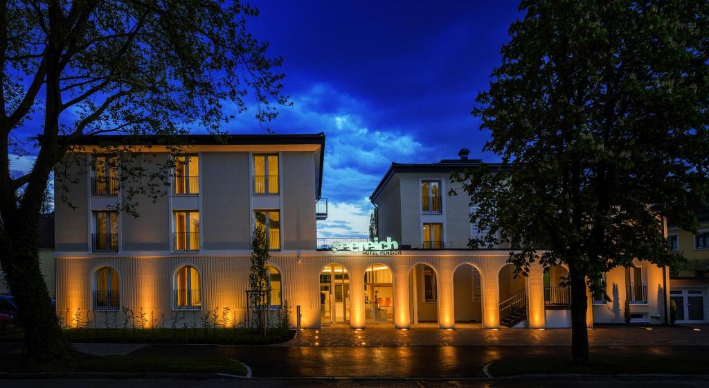 een groot wit gebouw met 's nachts verlichting bij Hotel und Pension Seereich in Lindau