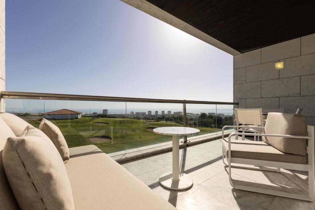 a room with a balcony with a table and chairs at Crowne Plaza - Caparica Lisbon in Costa da Caparica