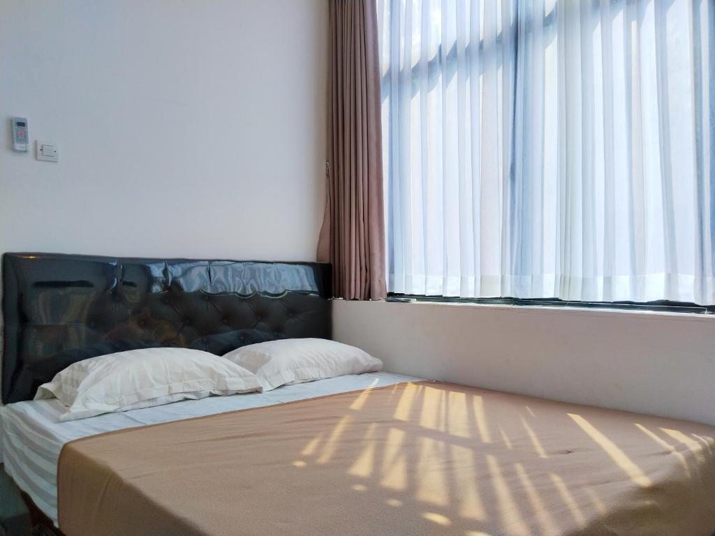 a bed with two pillows in a room with a window at Themas Guest House in Jakarta