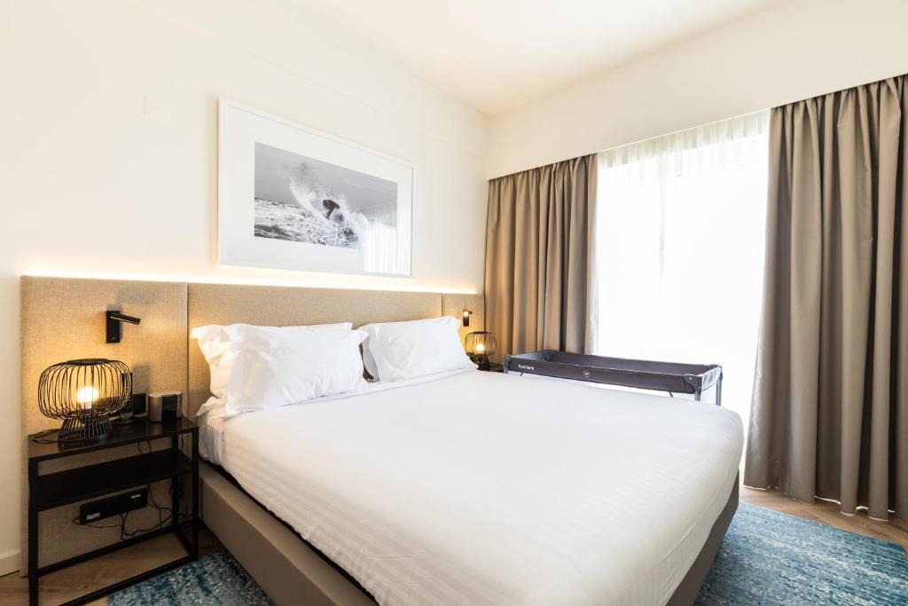 a hotel room with a large bed and a window at Crowne Plaza - Caparica Lisbon in Costa da Caparica