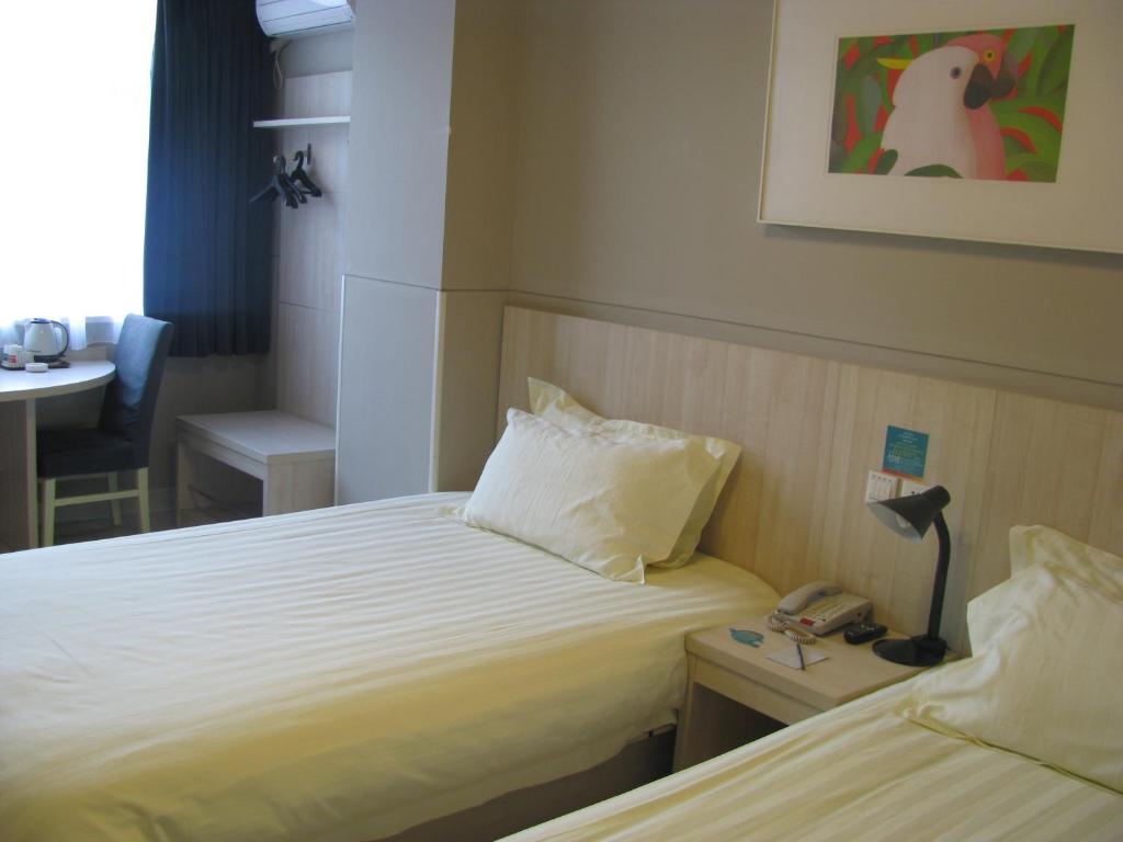 a hotel room with two beds and a telephone at Jinjiang Inn Qingdao Bus Station in Qingdao