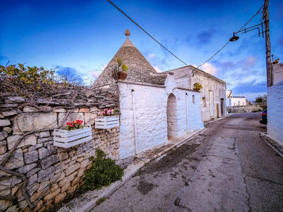 an old stone building with flowers on a street at Trullo Originale di Alberobello in Alberobello