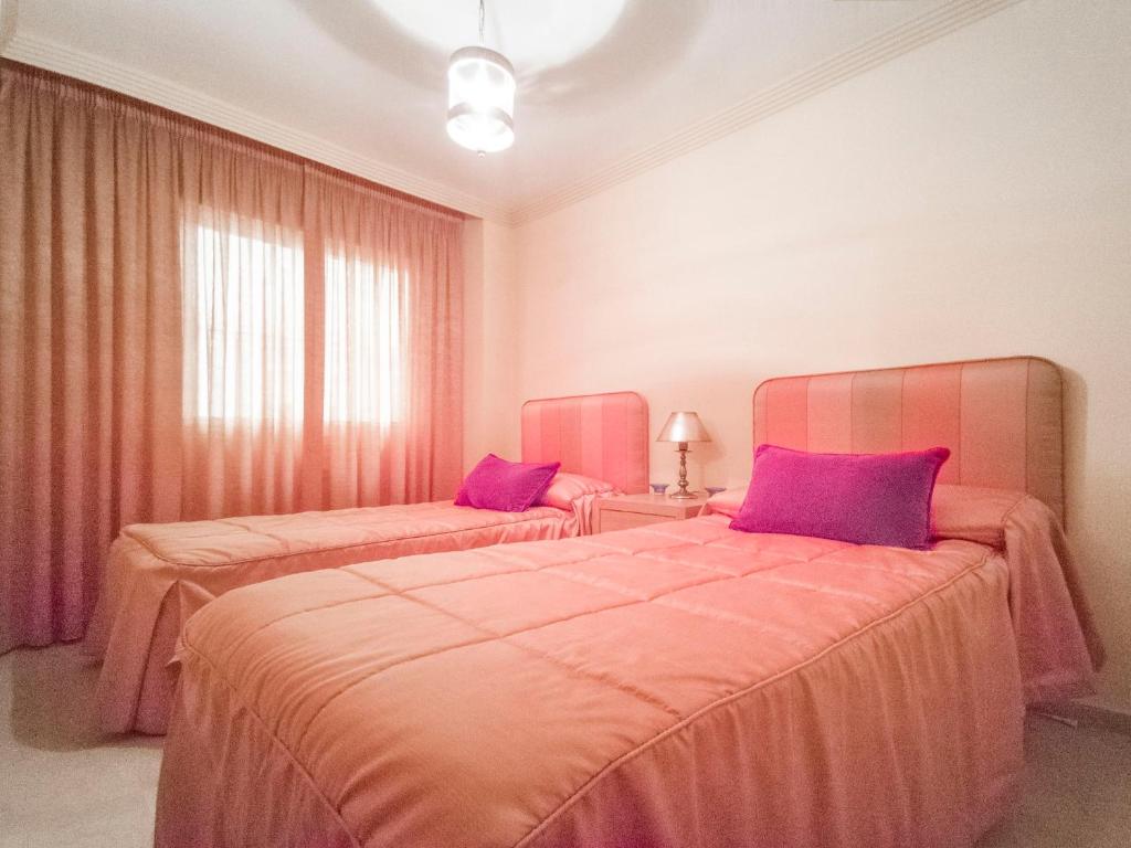 two beds in a room with pink and purple pillows at Banana Beach in Marbella