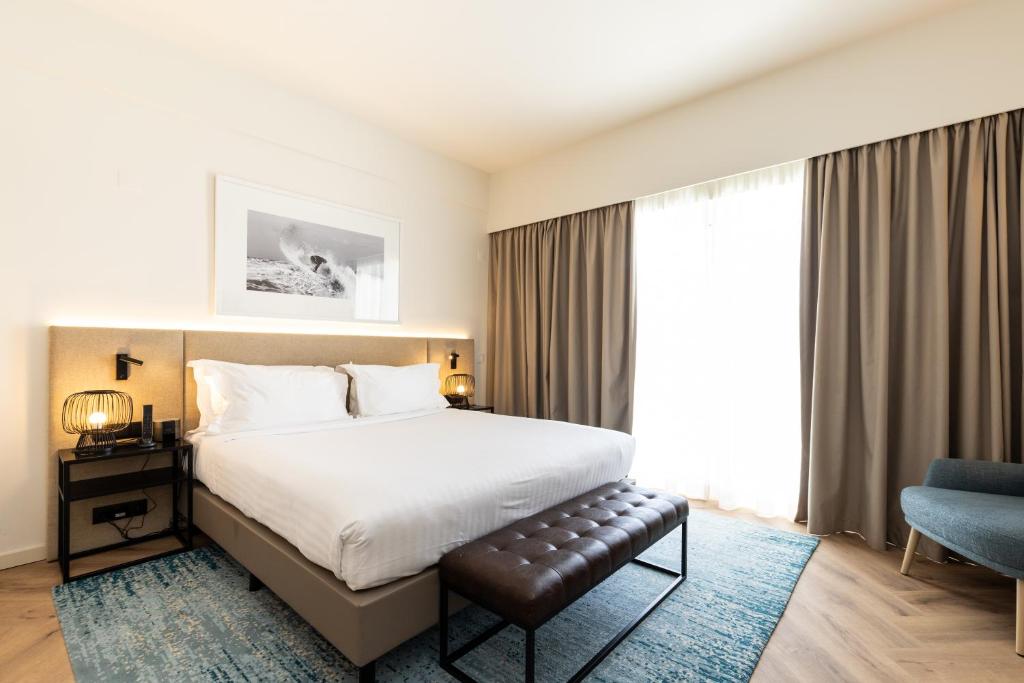 a hotel room with a bed and a chair at Crowne Plaza - Caparica Lisbon in Costa da Caparica