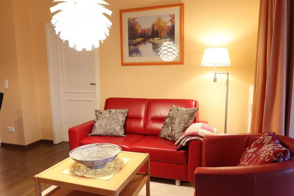 a living room with a red couch and a table at Dünenschloss - 02-29 in Kühlungsborn