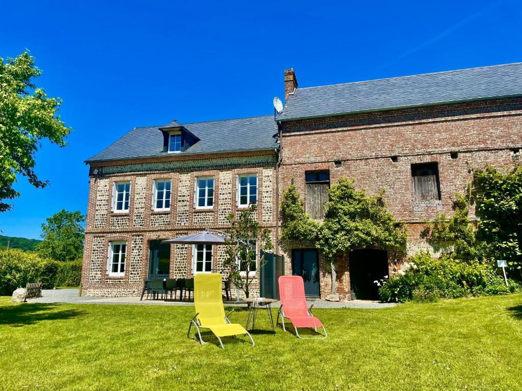 three chairs and a table in front of a building at Le Moulin de Mautheville in Grainville-la-Teinturière
