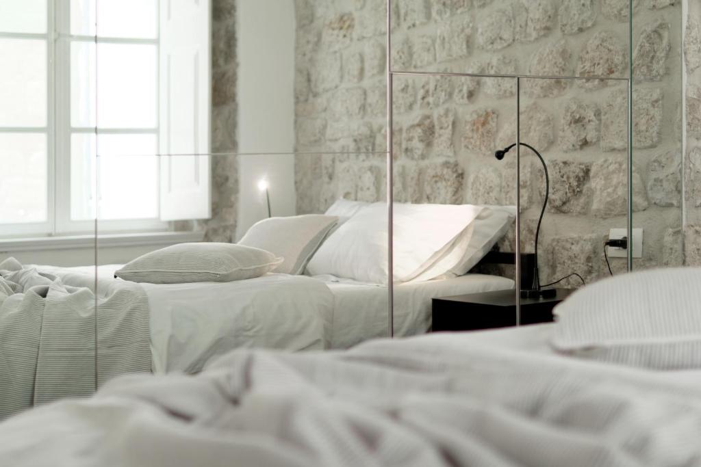 Apartments Eleganca-Comfort One Bedroom Apartment Djelozija في دوبروفنيك: غرفة نوم بيضاء بسريرين ومرآة