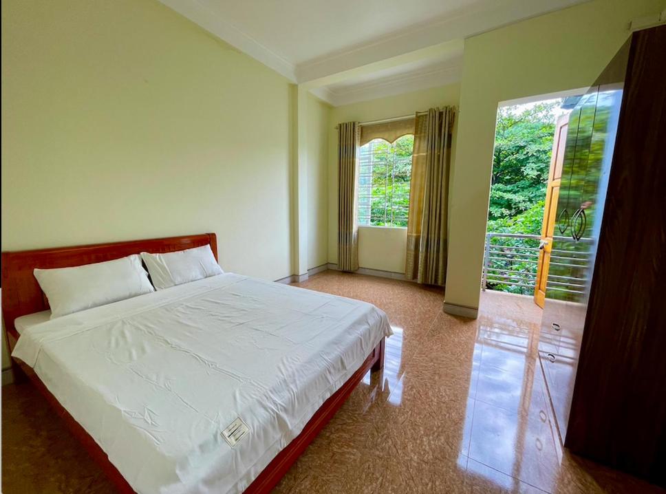 a bedroom with a white bed and a large window at Gem Market Guest House in Yên Bái