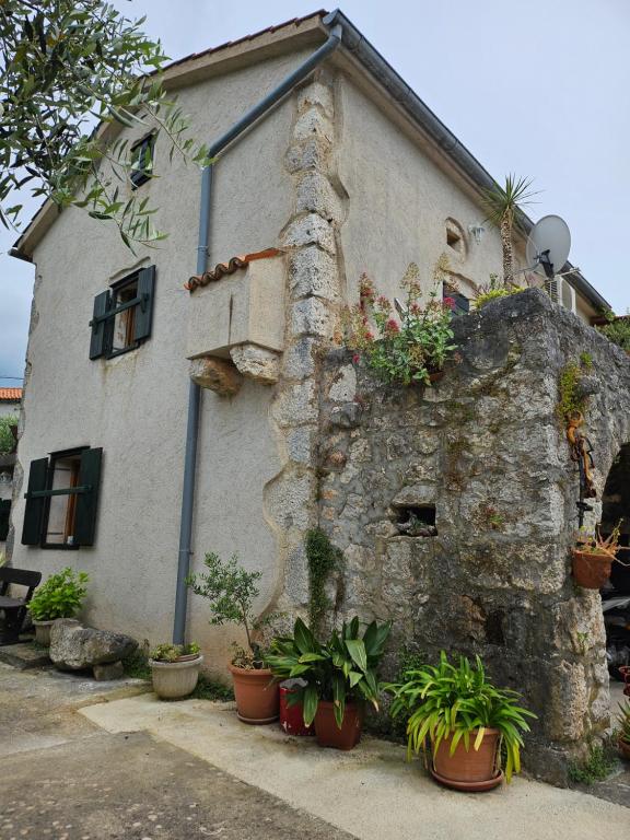 a building with potted plants on the side of it at Apartmani Purić in Malinska
